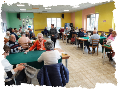 Persone di diverse età che giocano a carte attorno a un tavolo in un centro ricreativo