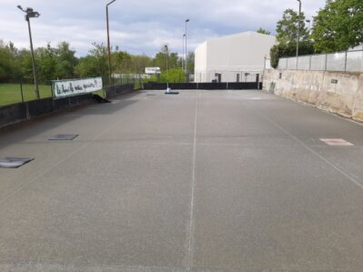 Mani che lanciano una boccia su un campo di bocce all’aperto