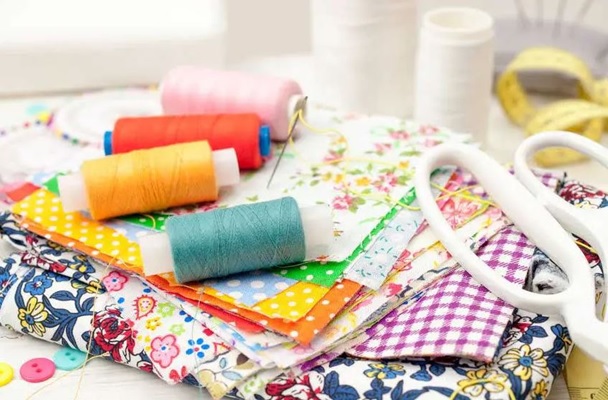 Tavolo con stoffe colorate e materiali per cucito creativo