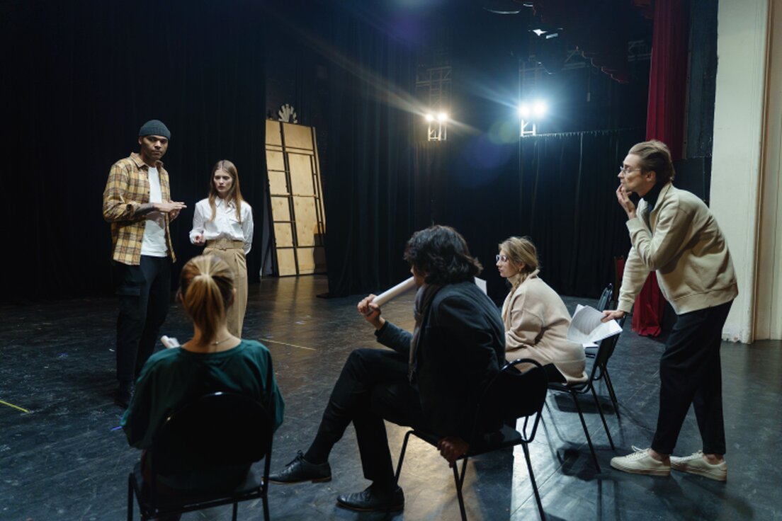 Piccolo gruppo che prova una scena teatrale in un salone di paese
